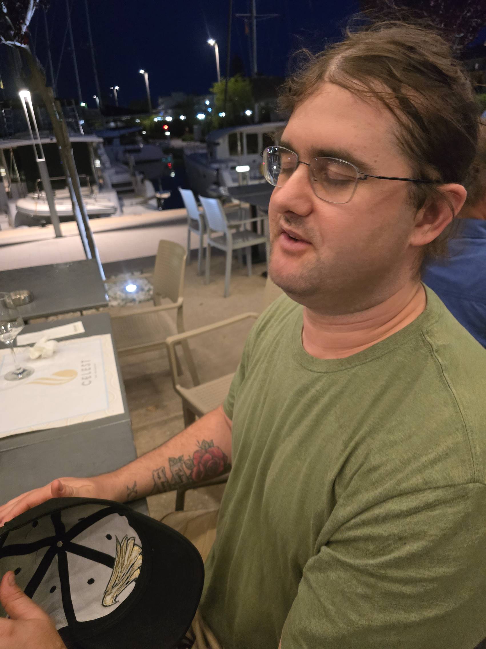 A person wearing glasses and holding a hat

Description automatically generated