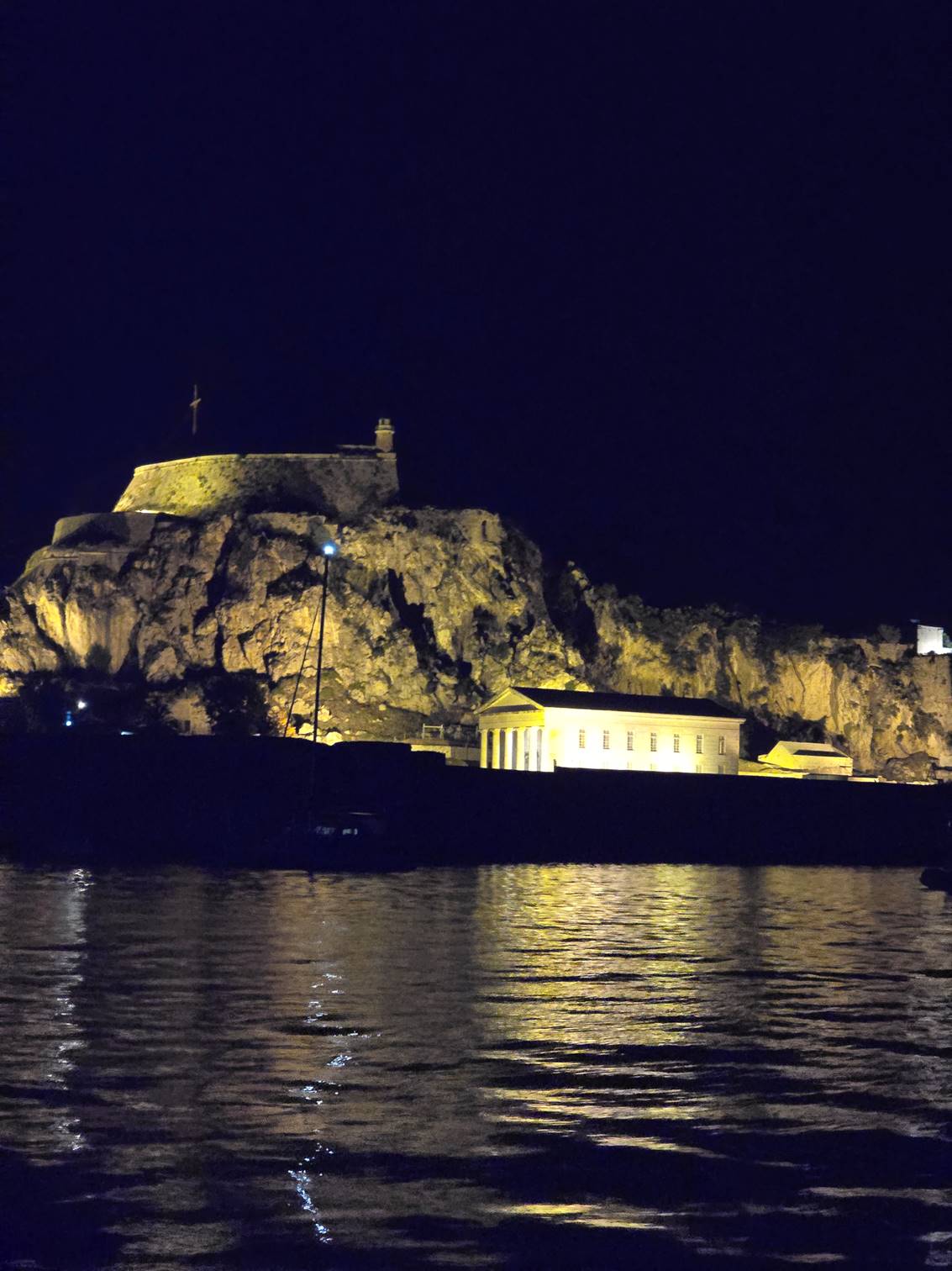 A building on a rocky hill by water

Description automatically generated