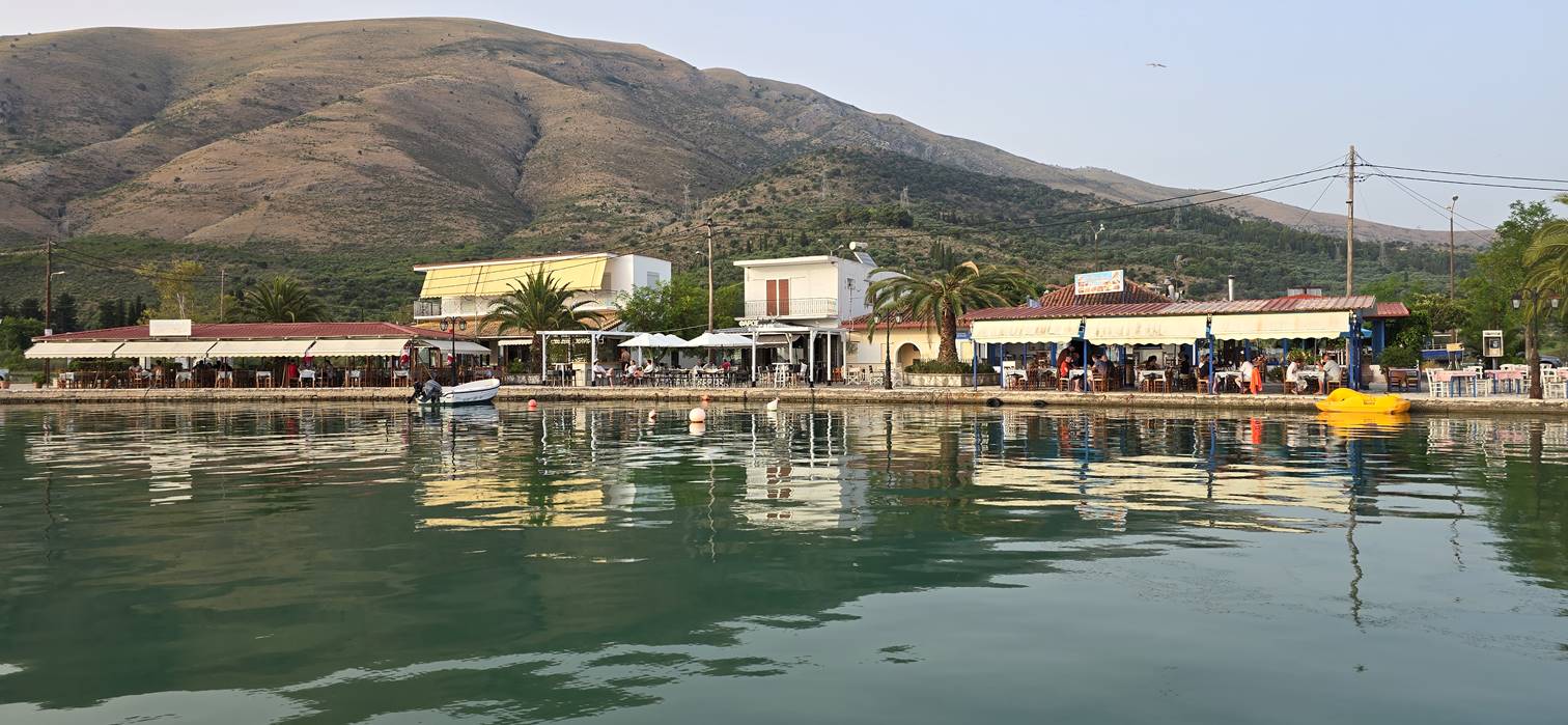 A body of water with buildings and mountains in the background

Description automatically generated